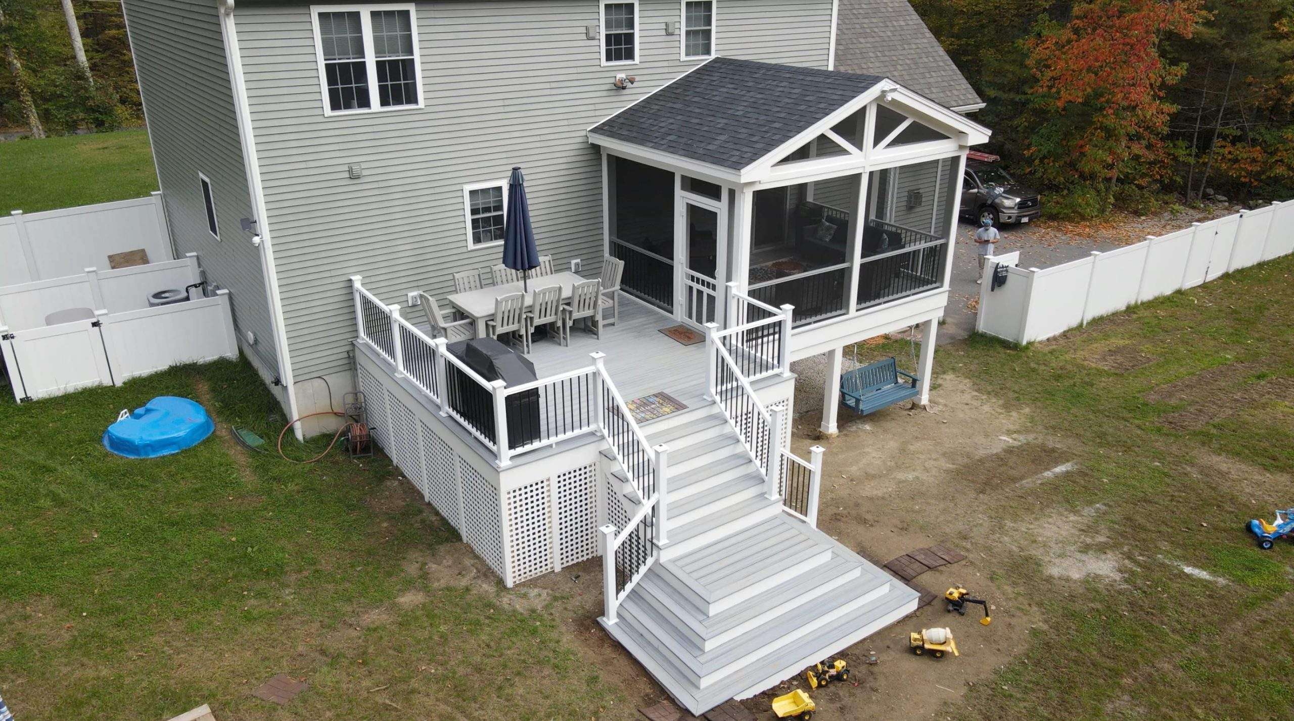 Aerial view of the home home with raised commercial deck with skirting and covered porch with outdoor living furniture in worcester ma