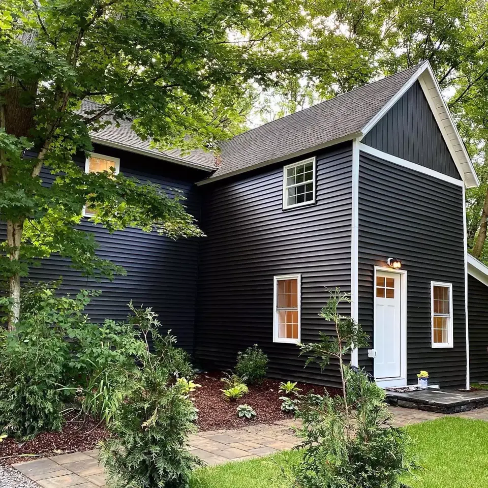 Black house with siding installation featuring trees and grass on the background in worcester ma