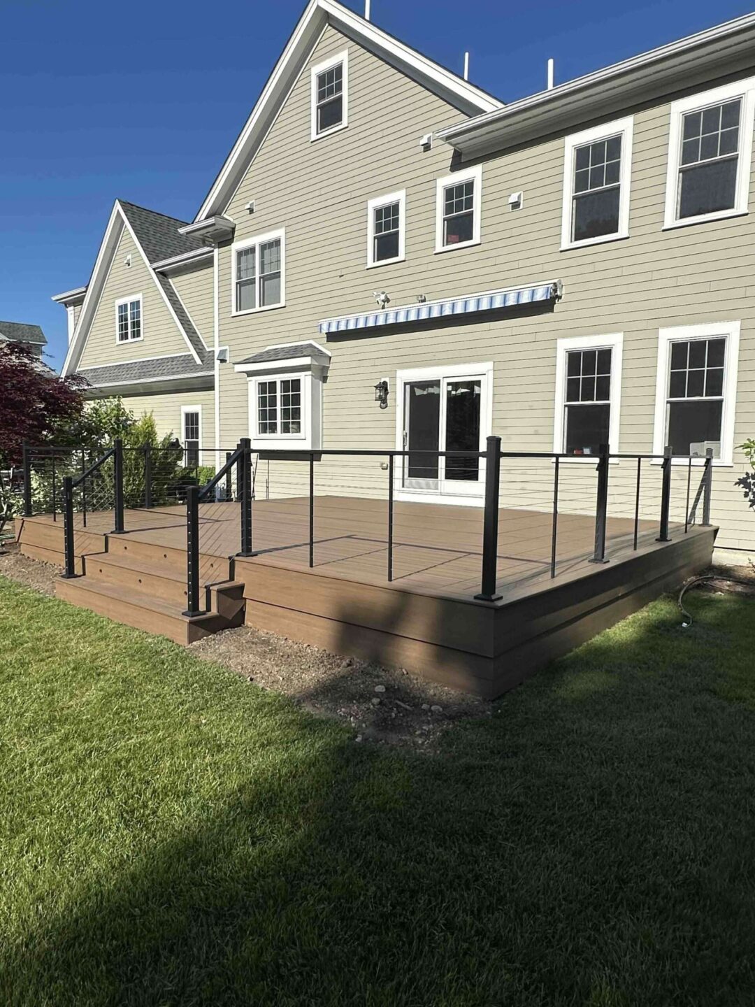 Composite deck with cable railing on the mocha house with sliding glass door in worcester ma