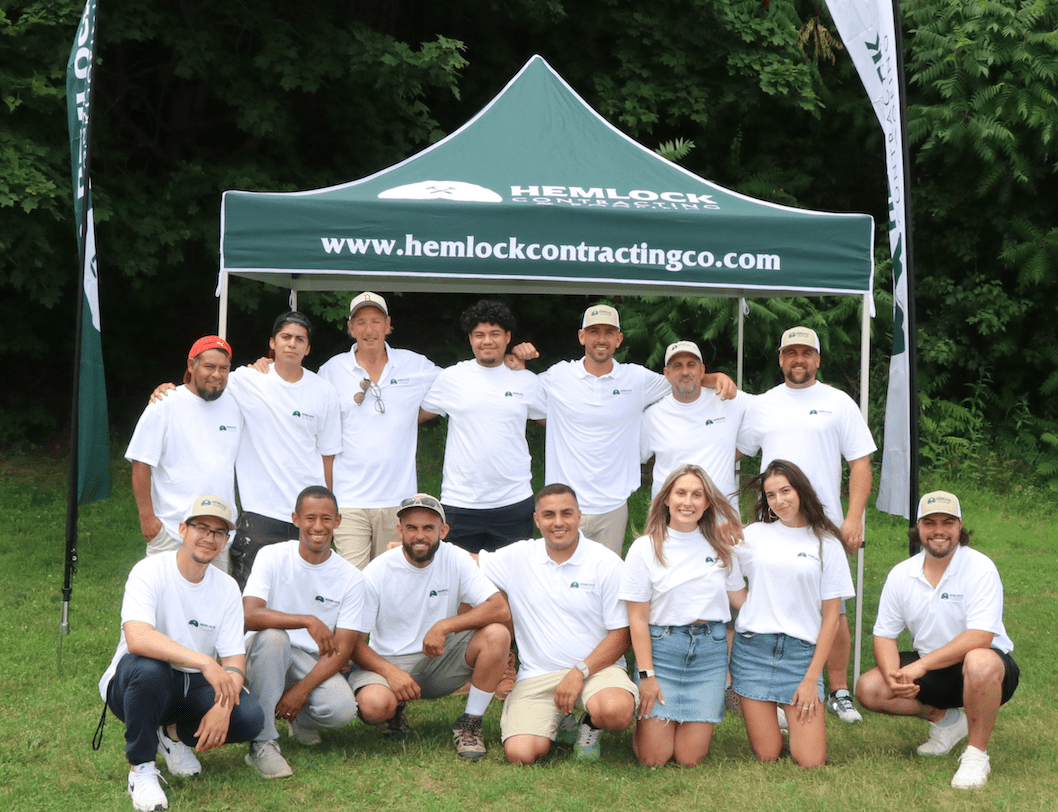 Hemlock contracting team on white tshirt featuring trees on the background in worcester ma