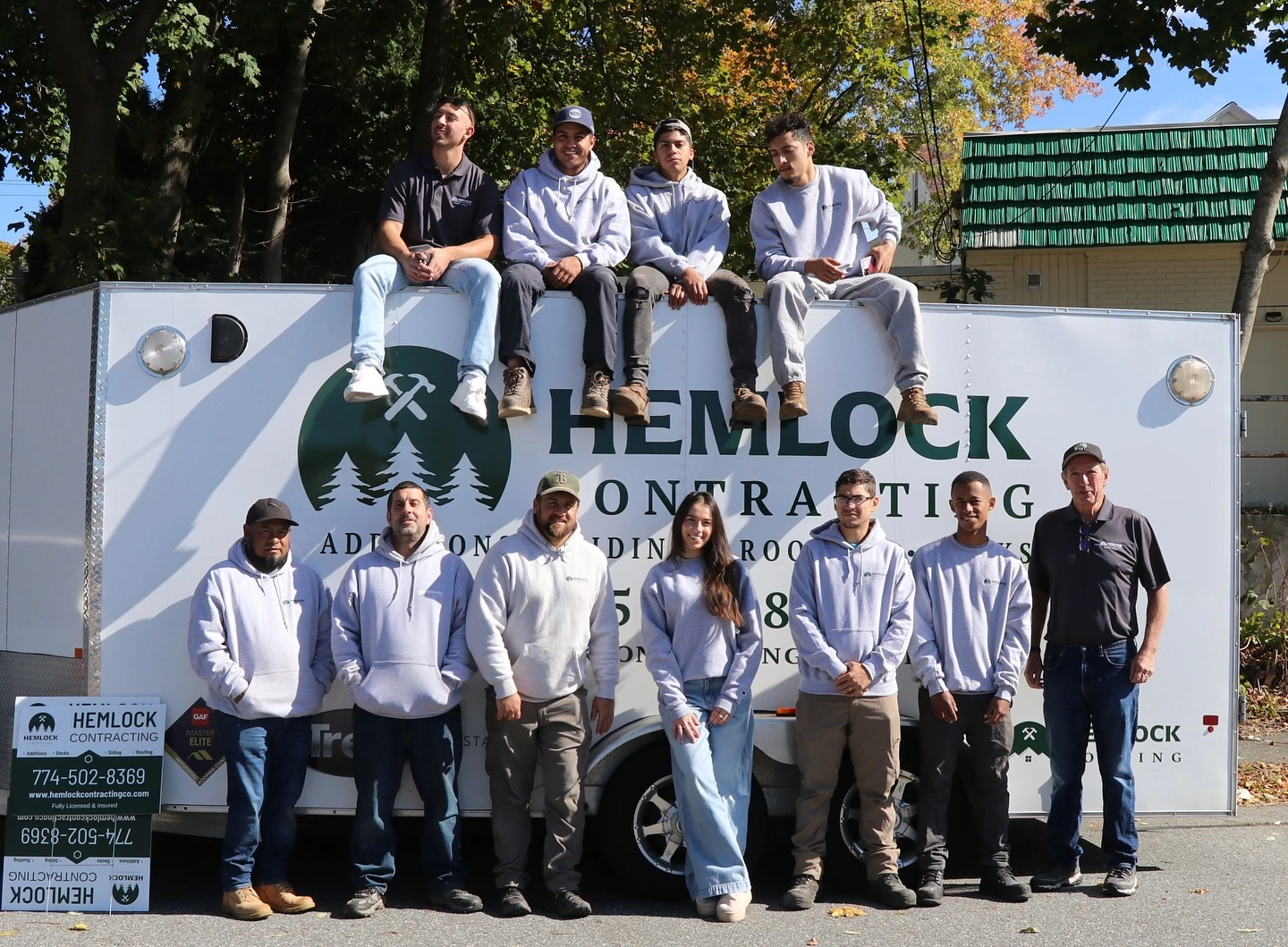 Hemlock contracting team posing in front and on top of their branded vehicle in worcester ma