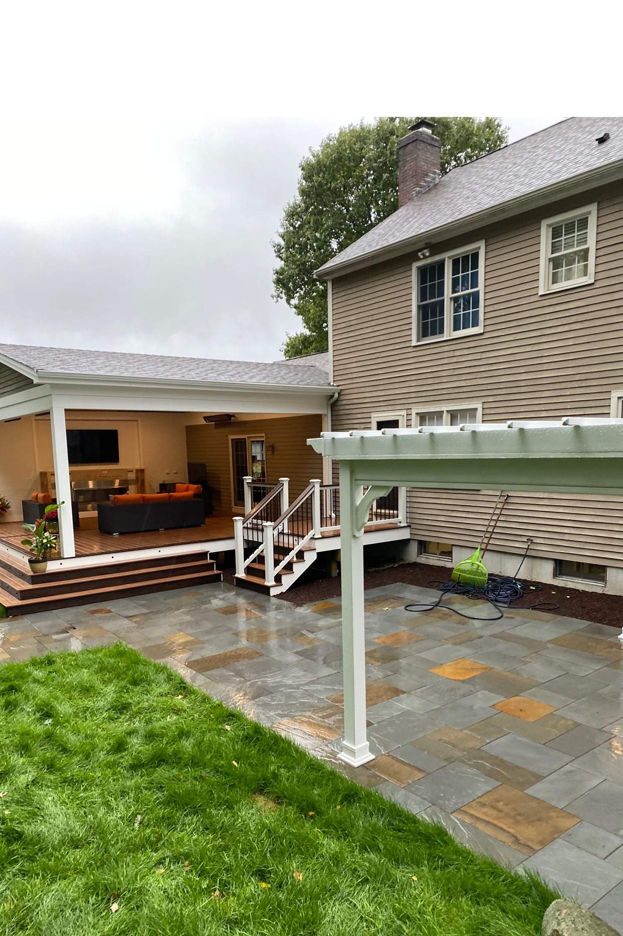 Pergola attached on a patio with a ground level deck and outdoor living furniture in worcester ma