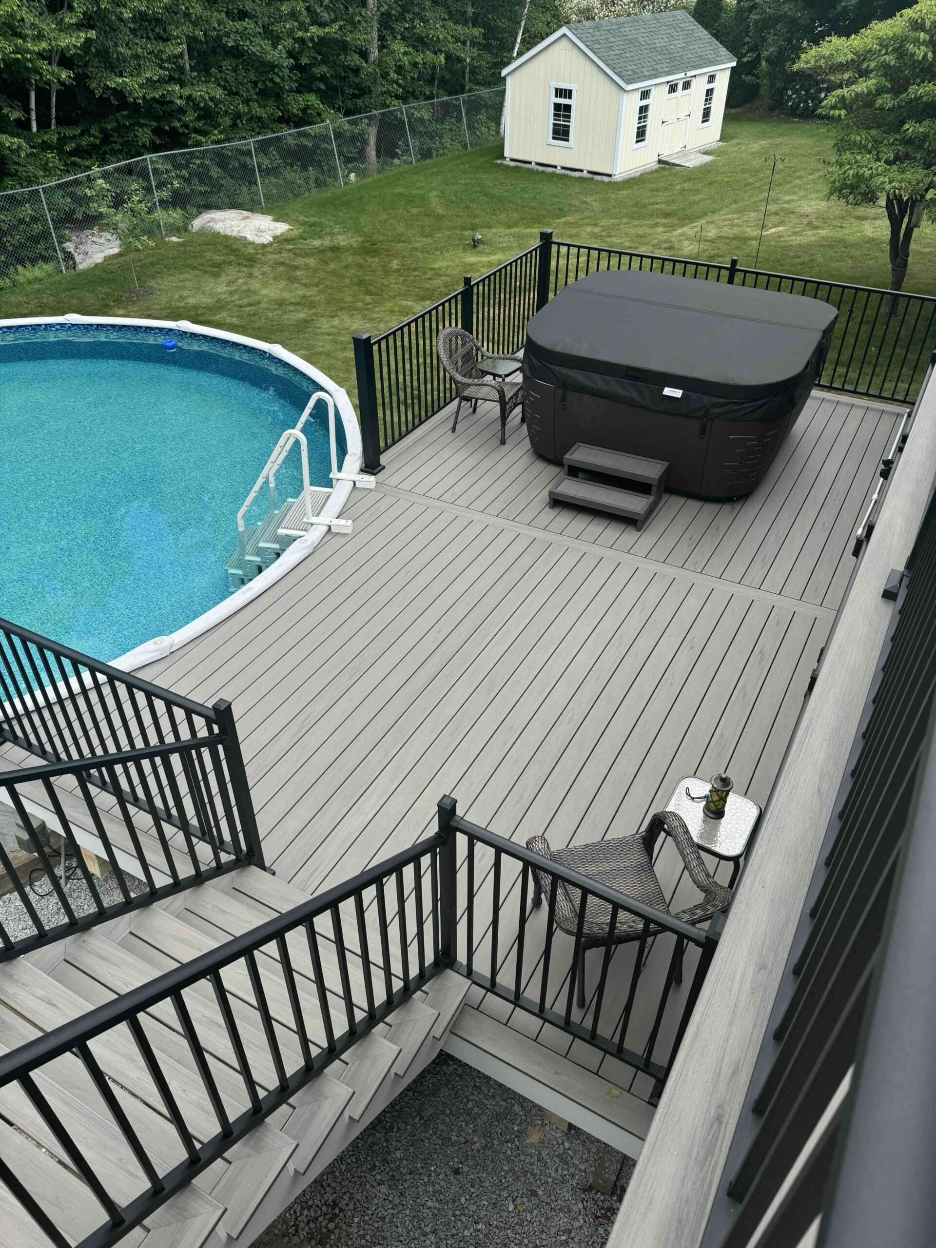 Pool deck installation on the pool with black aluminum railing with chairs in worcester ma