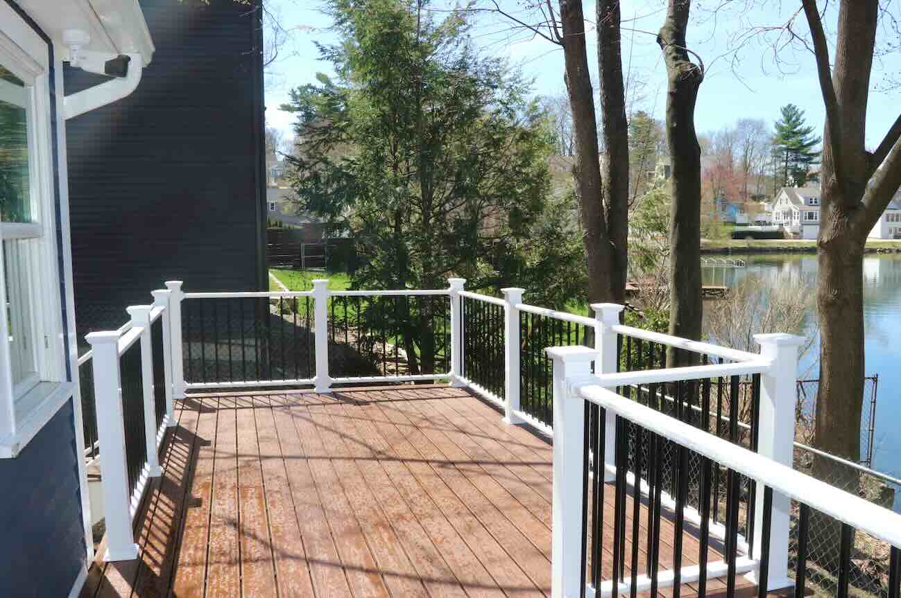 wet-hard-wood-deck-with-black-railing-and-wire-mesh-fence-below-the-deck-with-overlooking-lake-view-in-worcester-ma.jp